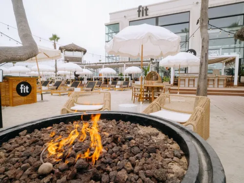 A firepit sits in the foreground of the outdoor patio area at FIT Social in the Pacific Beach community of San Diego. 