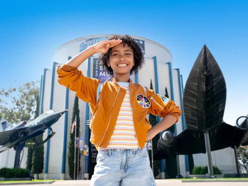 Young girl salutes outside of the San Diego Air & Space Museum in San Diego's Balboa Park