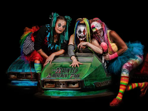 Three scary zombie women on a roller coster car looking at the camera at the haunted amusement park in San Diego
