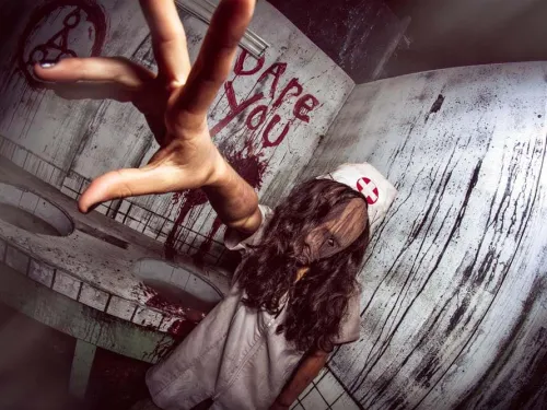 A haunted house employee, a zombie nurse grabbing for the camera on the haunted trails in San Diego