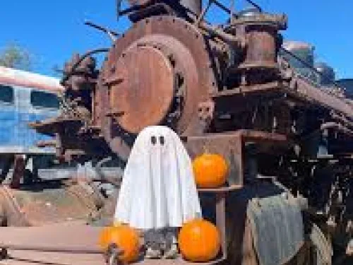 A small ghost in front of a train with pumpkins