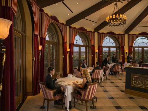 People dining in low light restaurant of ADDISON looking at golf course