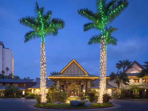 Two palm trees covered in lights with Holiday decorations adorning the entryway of the Catamaran Resort in San Diego's Mission Bay