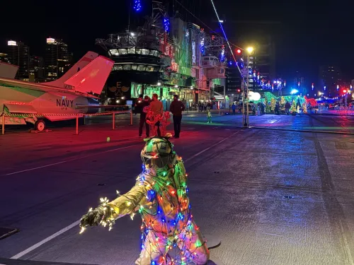 A figure draped in Christmas lights crouches on the deck of the USS Midway Museum during the Jingle Jets holiday event in beautiful San Diego.