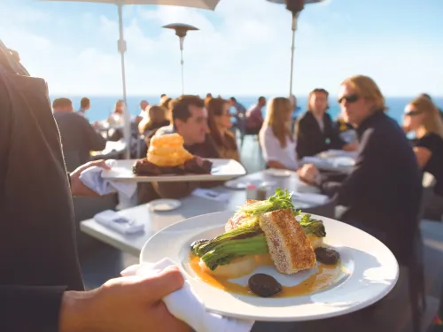 Server bring dinner plates to diners at George's at the Cove in San Diego's La Jolla