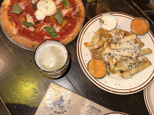 Pizza and french fries paired with beers next to a menu at Blind Lady Ale House in Normal Heights neighborhood of San Diego, CA