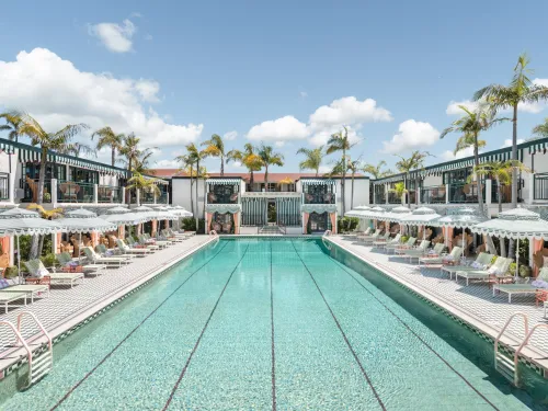 Large blue pool lined with chairs and rooms at the Lafayette Hotel in San Diego, CA