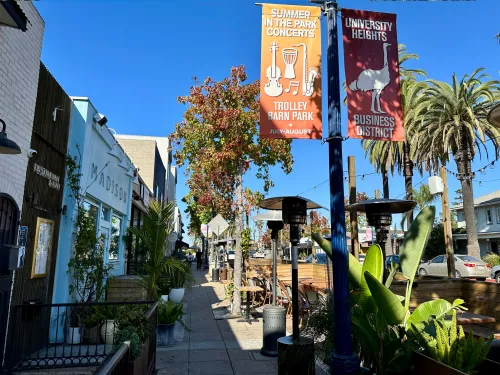 Restaurants along Park Blvd. with outdoor seating and colorful trees and signage in University Heights