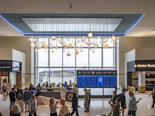 Travelers waiting at Terminal 1 San Diego Airport with art overhead