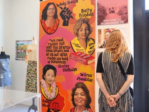 A woman standing in front of an art instillation honoring women of the past, at a museum in San Diego, CA.