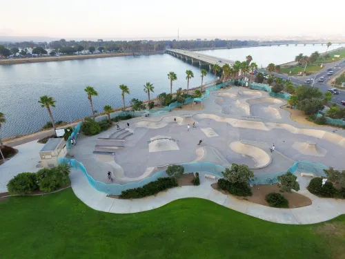 Aerial view of Robb Field skate park in Ocean Beach, San Diego, showing skaters, palm trees, and the river alongside the park.
