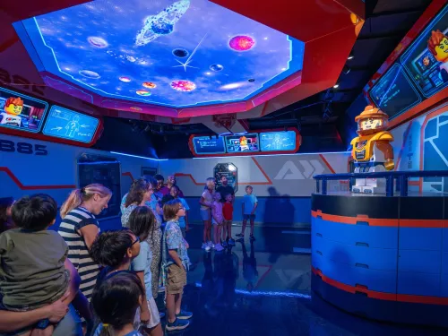 A group of children and adults watch a robot character in a colorful, futuristic room that's part of LEGO Galaxy at the LEGOLAND California Resort in Carlsbad near San Diego.