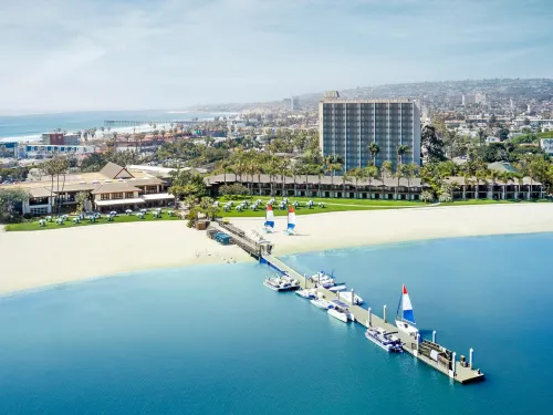 Aerial view of the Catamaran resort with a pier, surrounded by water and cityscape in the background.