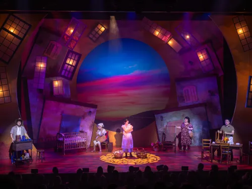 Actors work onstage against a colorful, lighted backdrop during the Cygnet Theatre production of "Somewhere Over the Border" in San Diego.