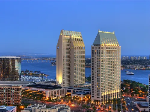 Skyline view of two tall buildings at dusk, overlooking a waterfront with boats.