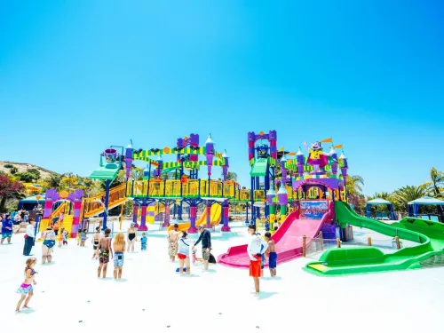 Colorful water playground at Sesame Place with slides, surrounded by children playing under a clear blue sky.