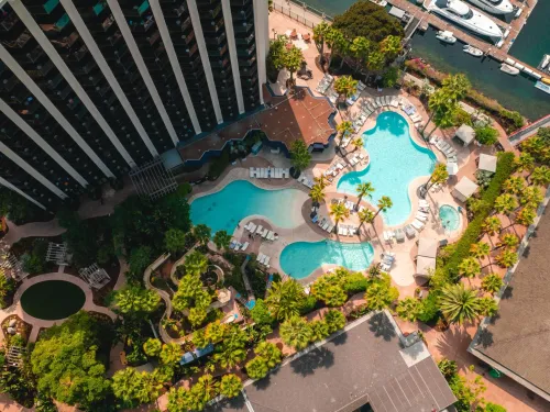Aerial view of swimming pools surrounded by palm trees and buildings at the Hyatt Regency Mission Bay Spa & Marina in San Diego