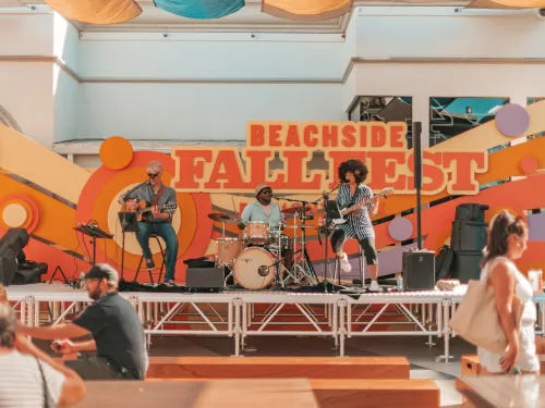 Three musicians performing on stage at the lively Beachside Fall Fest at Belmont Park.