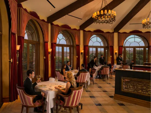 People dining along windows at dusk at ADDISON in the Fairmont Grand Del Mar