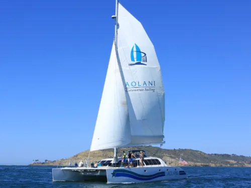 The large Aolani Catamaran Sailing boat and white sail head out on the water