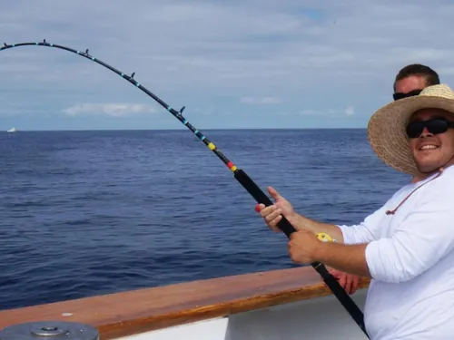 Person holding a fishing pole on an H&M Landing boat with it coming out of the San Diego Bay waters