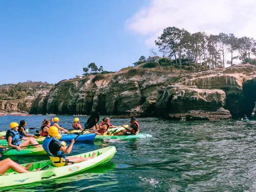 People on the ocean kayaking through La Jolla's sea caves in San Diego, CA