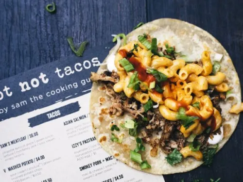 Taco with mac & cheese and meat on a menu in Little Italy of San Diego, CA