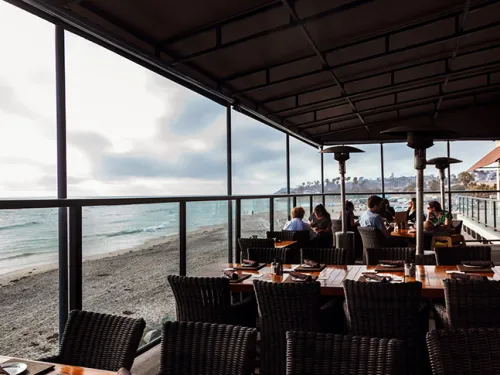 People dining next to the beach at Pacific Coast Grill in San Diego, CA