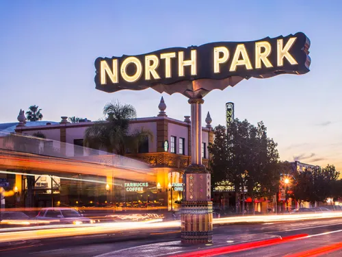 Cars zooming past lit up North Park neighborhood sign