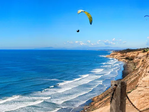 Paraglider flying over Torrey Pines Gliderport over the ocean in San Diego, CA