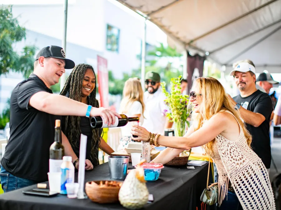 two people getting wine poured into their glass at the La Jolla Wine and Food Festival in San Diego on a sunny day.