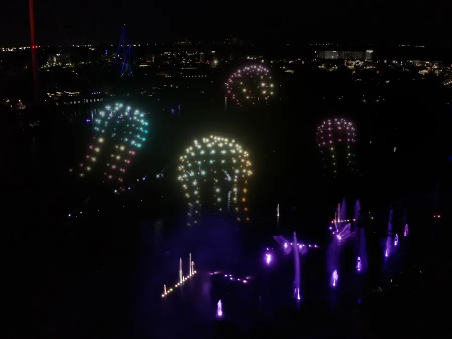 Colorful illuminated jellyfish drone show at night, surrounded by city lights.