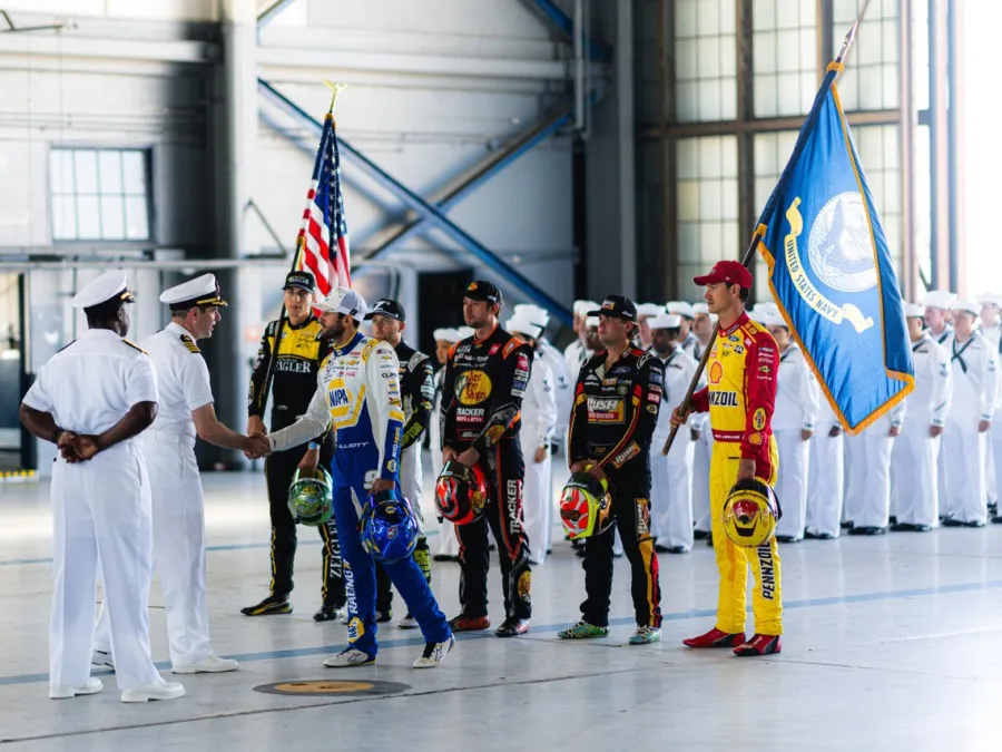 Navy representatives shake hands with NASCAR drives inside a hangar at Naval Base Coronado.