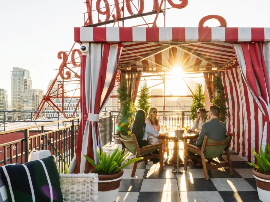A vibrant rooftop seating area atop the Pali Hotel with people chatting and sunlight streaming through.