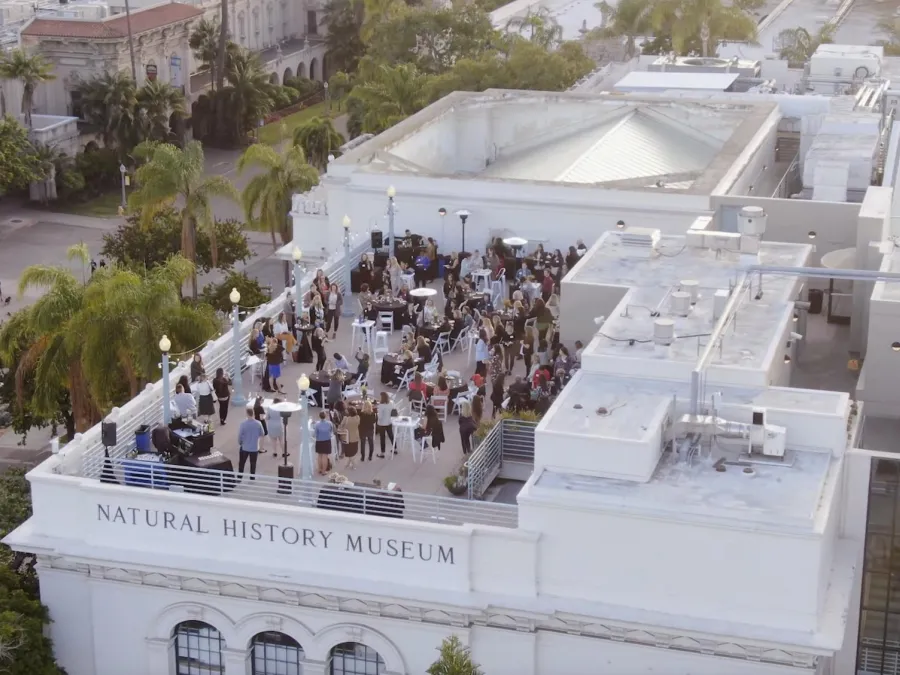 Crowd of people on the rooftop of the San Diego Natural History Museum at sunset.