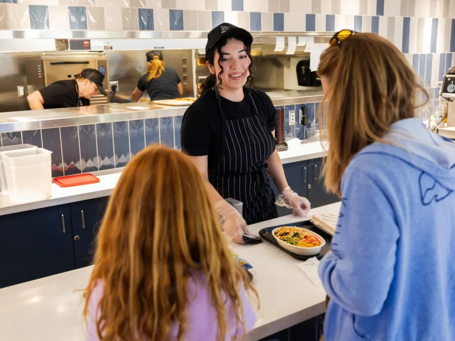 A female server assists two young girls at the modern Element 8 Cafe counter in a casual dining setting at the Fleet Science Center in Balboa Park.