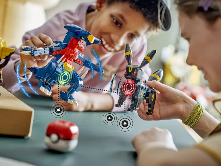 Two children engage with colorful LEGO Pokemon, excitedly interacting with them on a table at the summer LEGO Festival at LEGOLAND California.