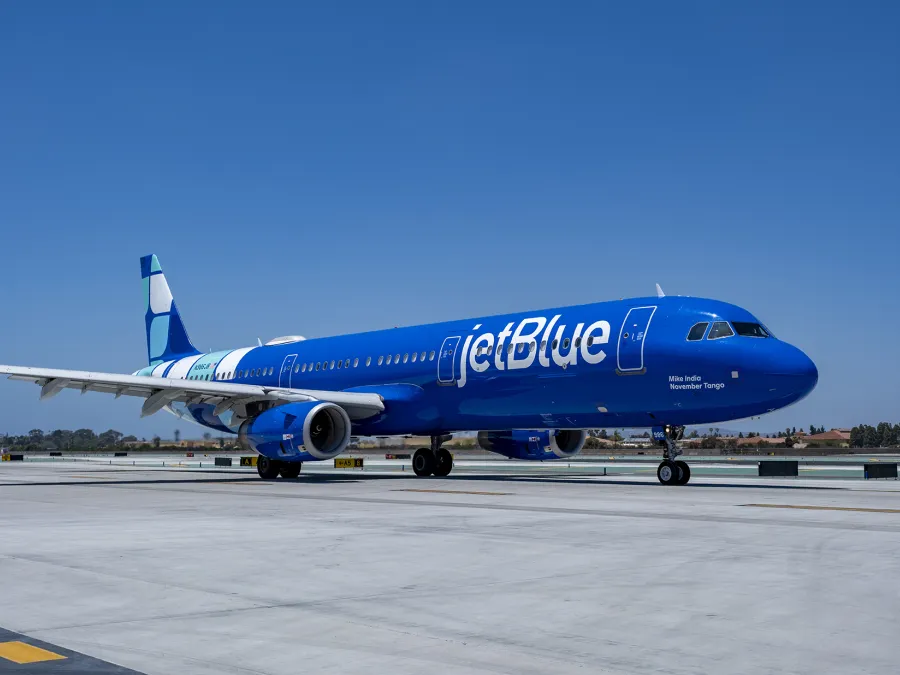 JetBlue airplane on the tarmac under a clear blue sky.