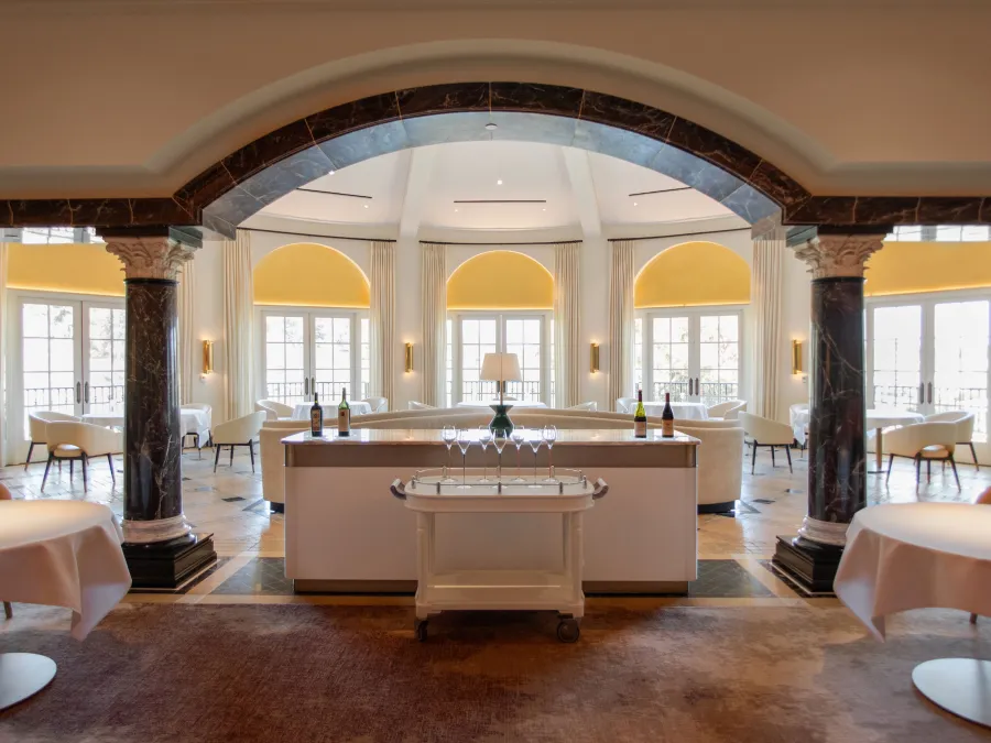 Elegant restaurant interior with high ceilings, arched entryway, and soft yellow lighting.