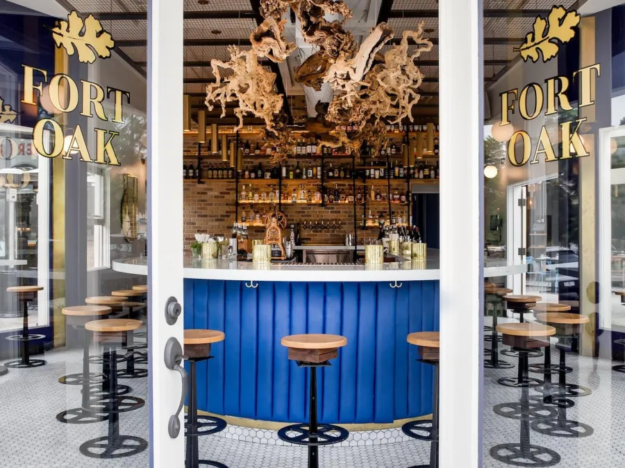 Stylish bar entrance to Fort Oak featuring a blue counter, decorative wood elements, and hexagonal tiles.