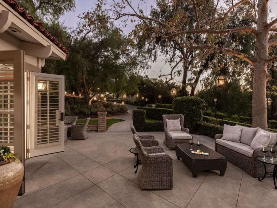 Elegant outdoor seating area at the Rancho Bernardo Inn in San Diego, with plush chairs and a coffee table, surrounded by lush greenery.