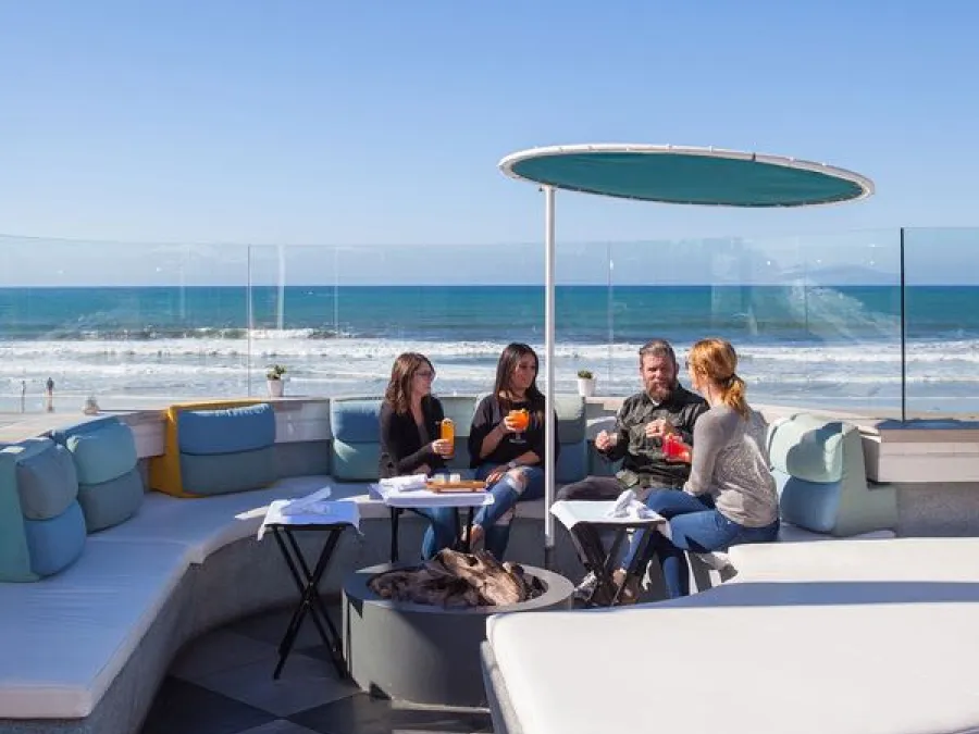 People dining with Mission Beach in the background at Belmont Park's Cannonball in San Diego, CA