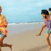 Kid gets piggy back ride from father while running on San Diego beach after mother
