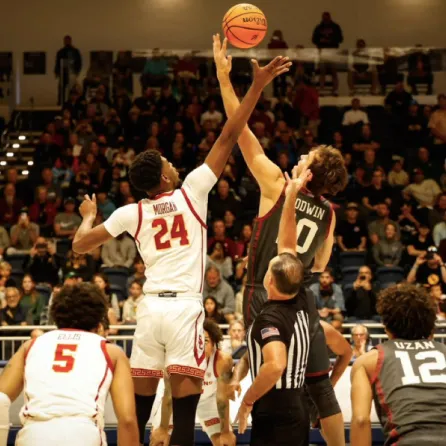 Two male college basketball players jumping up for a a jump ball at the start of a game at the Rady Children's Invitational in San Diego